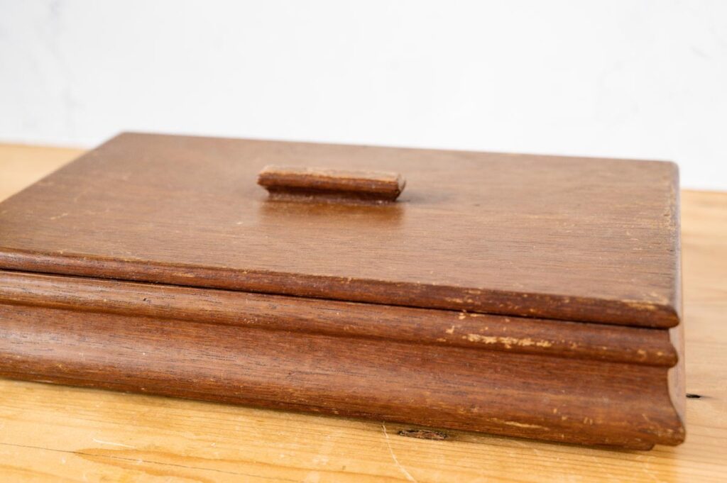 Plat rechthoekig vintage houten kistje met deksel en twee vakken op houten ondergrond