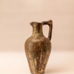 Handgemaakte aardewerken kruik met hoekig handvat en rustiek oppervlak