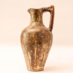 Handgemaakte aardewerken kruik met hoekig handvat en rustiek oppervlak