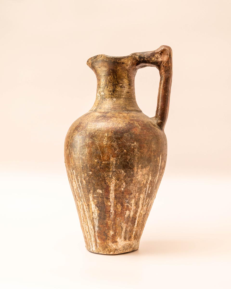 Handgemaakte aardewerken kruik met hoekig handvat en rustiek oppervlak