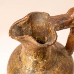 Handgemaakte aardewerken kruik met hoekig handvat en rustiek oppervlak