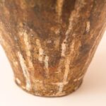 Handgemaakte aardewerken kruik met hoekig handvat en rustiek oppervlak