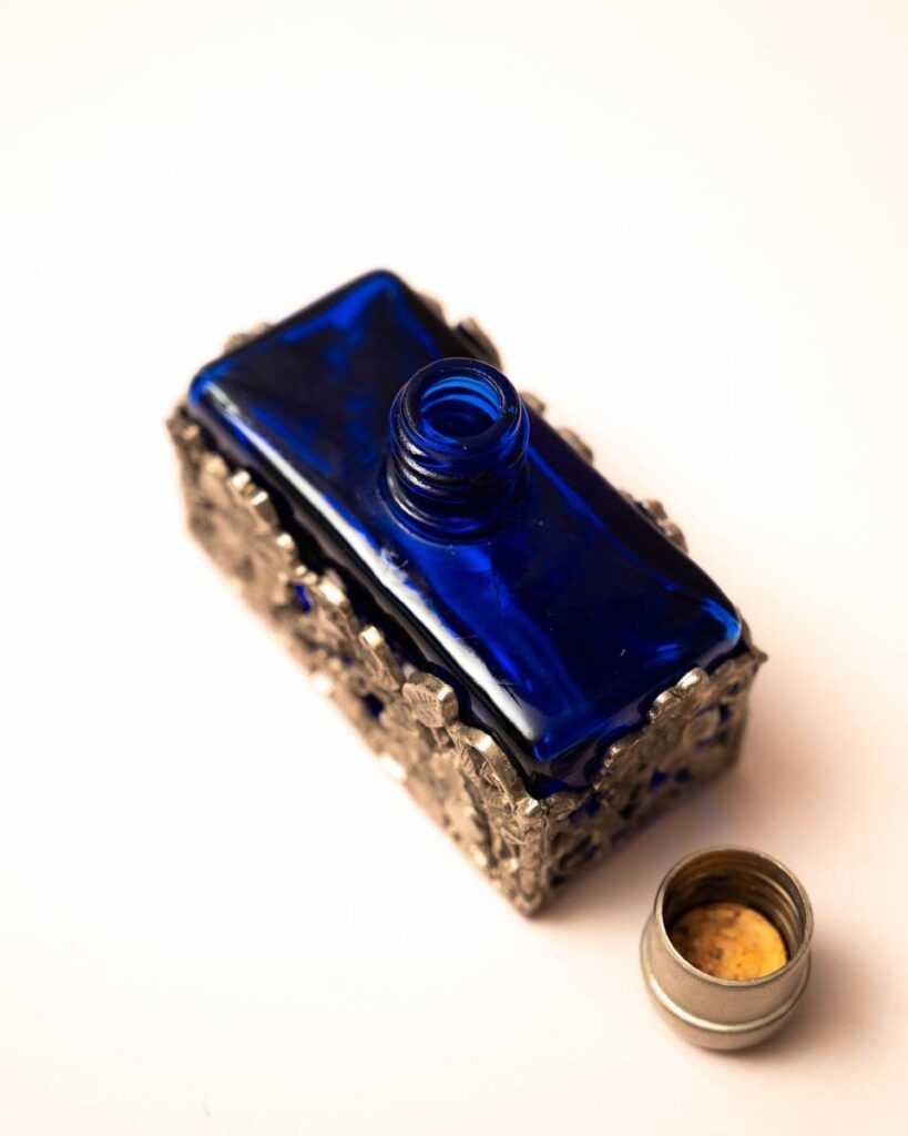Blauw glazen parfumflesje met tinnen bloemendecoratie