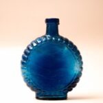 Platte blauwe glazen fles met schelprand