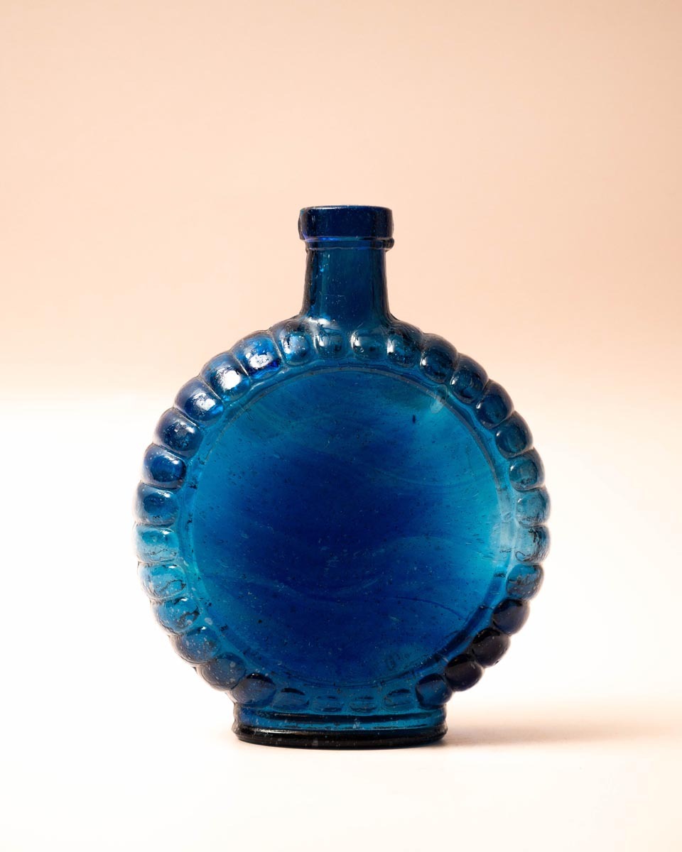 Platte blauwe glazen fles met schelprand