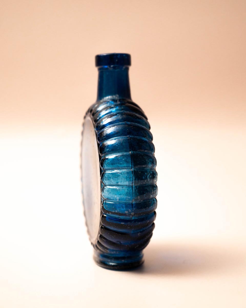 Platte blauwe glazen fles met schelprand