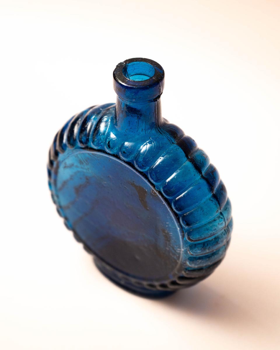 Platte blauwe glazen fles met schelprand