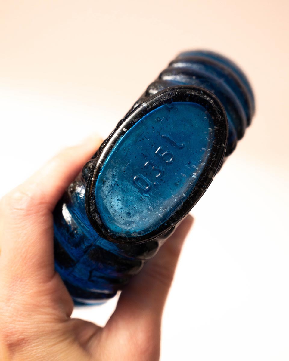 Platte blauwe glazen fles met schelprand