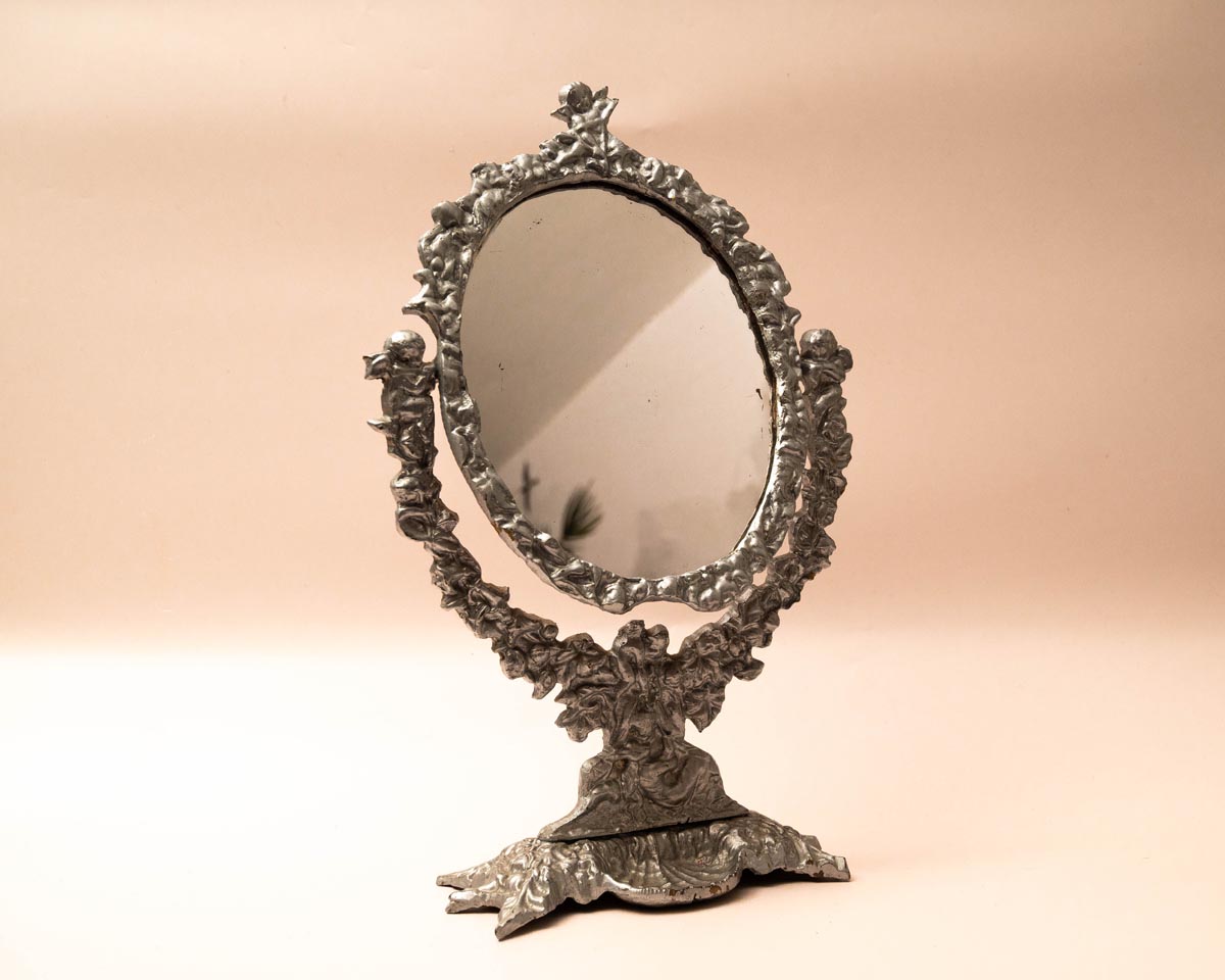 Ronde kaptafelspiegel op standaard met engeltjes decoratie en klein schaaltje